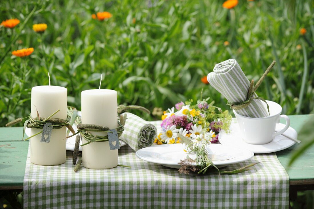 Candles and posy of wildflowers arranged on garden table