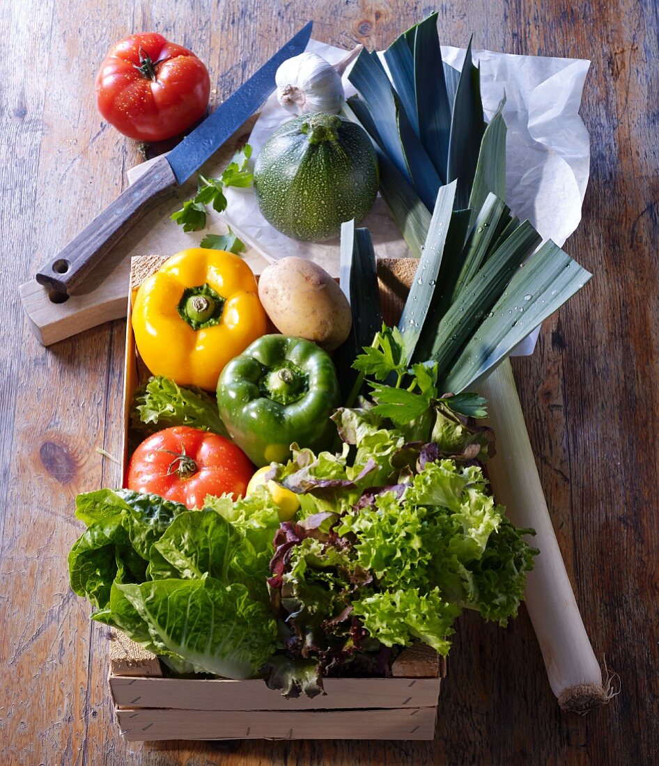 Market vegetables in a wooden box and on a wooden board with paper