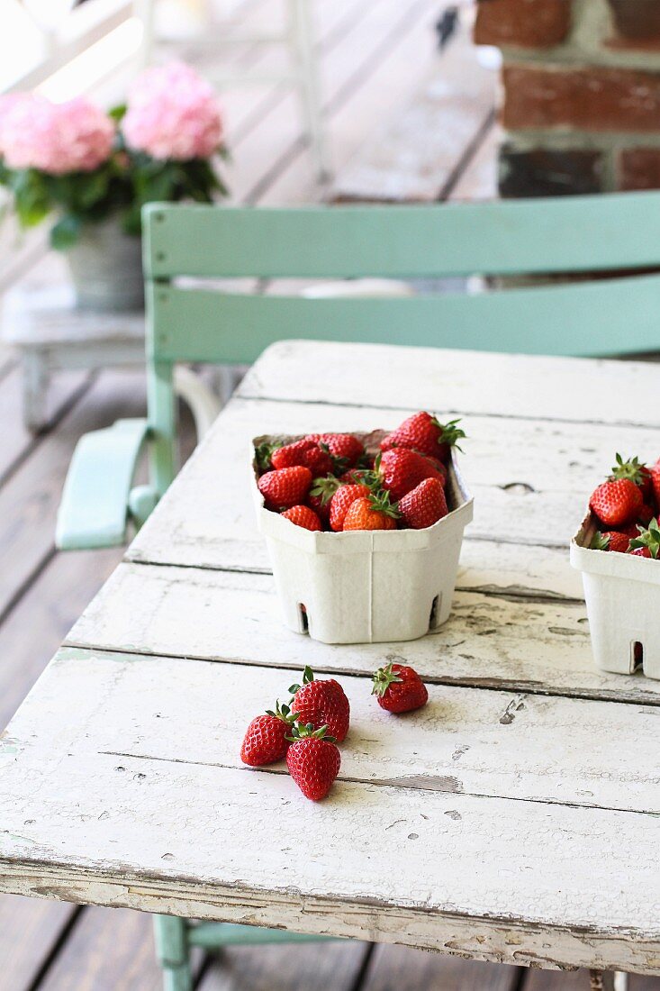 Erdbeeren in Pappschälchen auf Terrassentisch