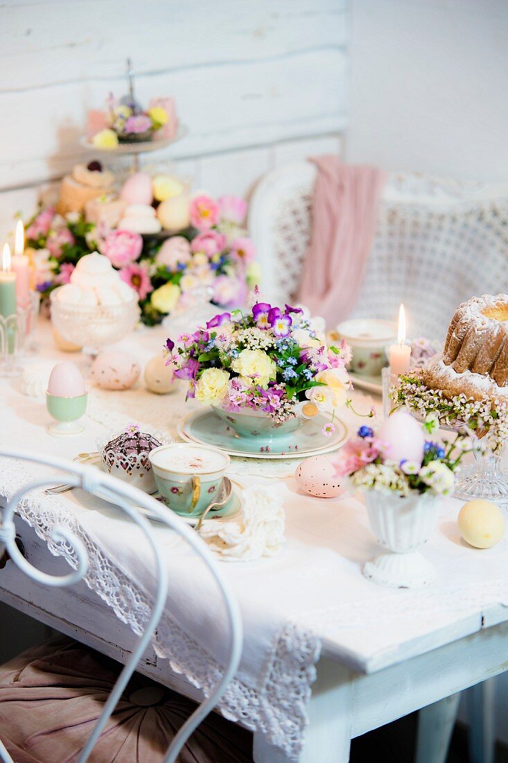 Easter table romantically set with delicate flowers and lit candles