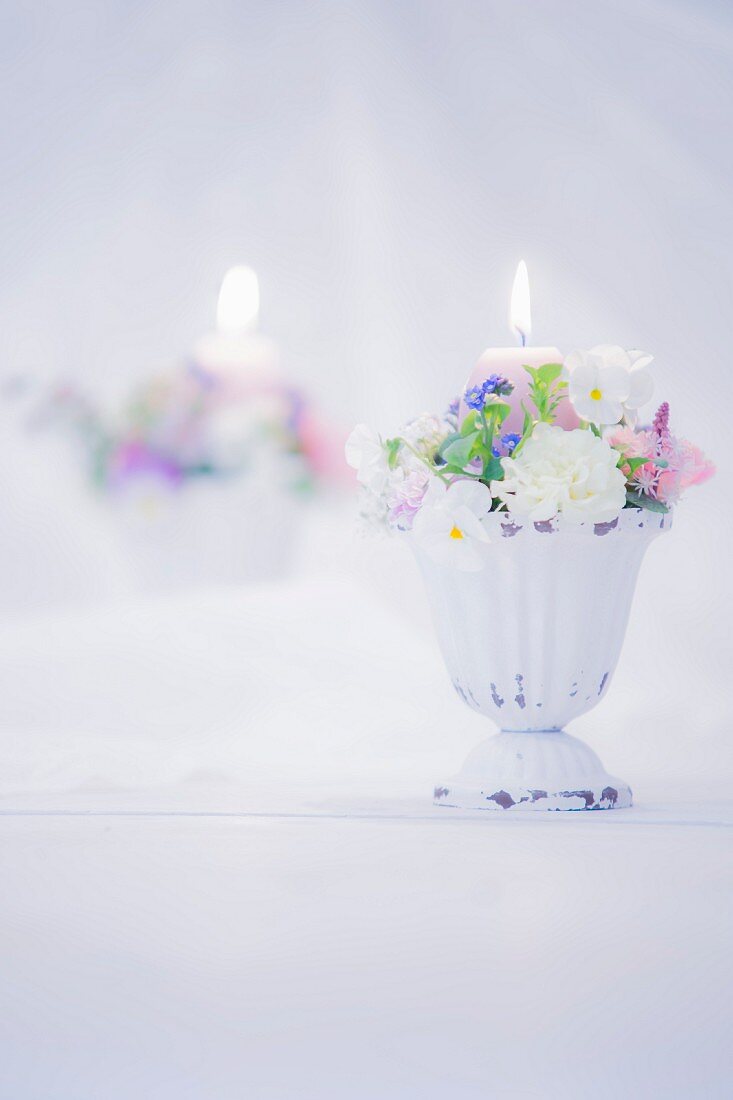 Romantic flower arrangement and lit candle in front of mirror