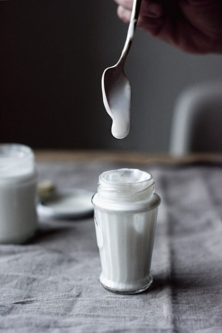 Coconut yoghurt dripping from a spoon into a glass