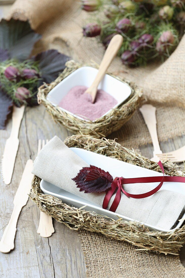 Rustic table decoration with hay trays, wooden cutlery and jute table runners