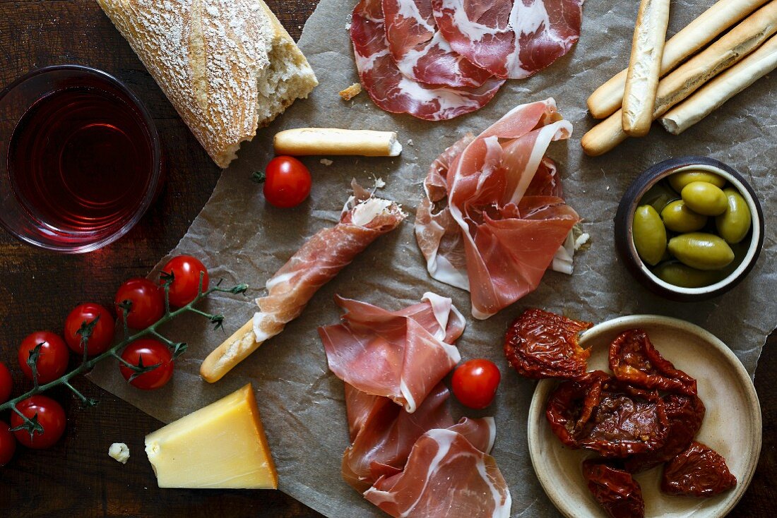 Italian antepasto spread on wrinkled wax paper and dark wooden board