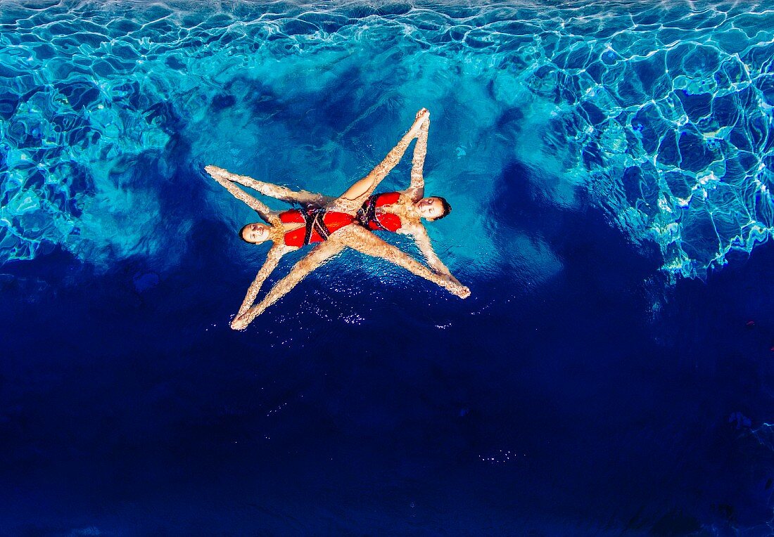 Two synchronised swimmers forming a shape in the water (seen from above)