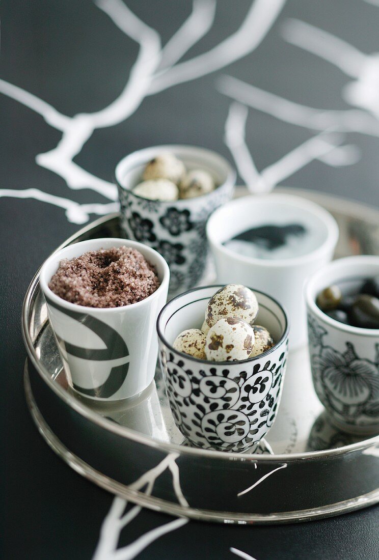 Quail eggs in porcelain beakers on tray