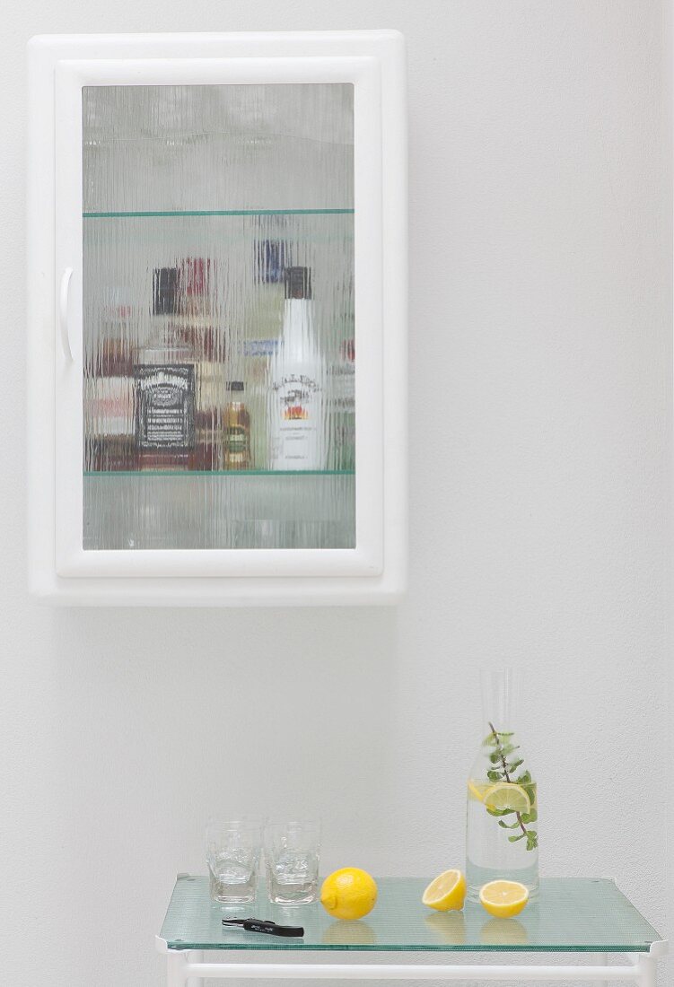 Bottles of alcohol in glass-fronted cabinet above drinks trolley