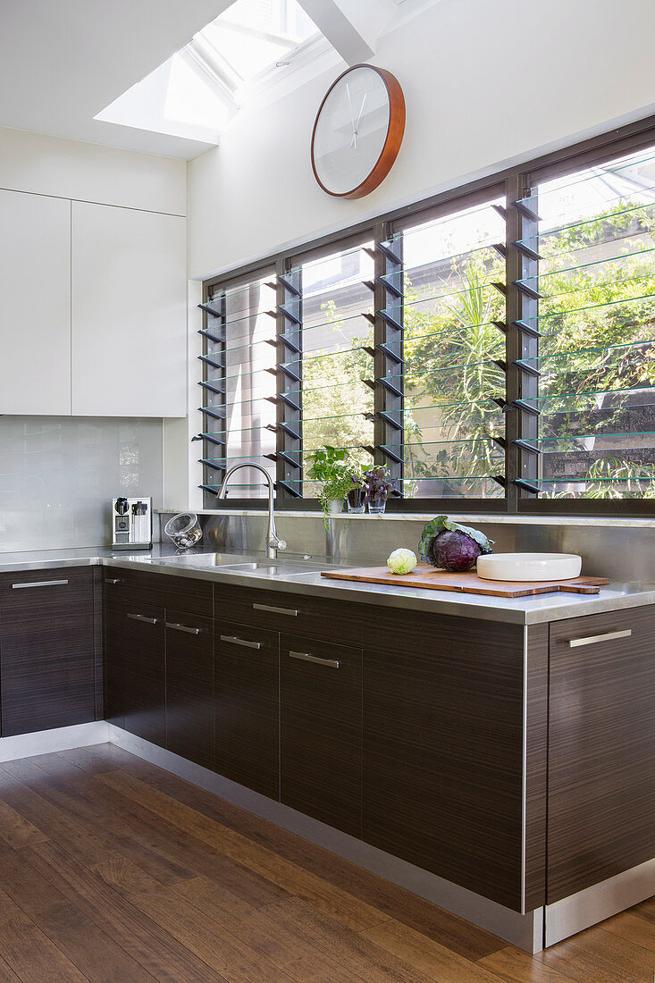 Moderne Küche mit dunklen Holzfronten und Lamellenfenstern