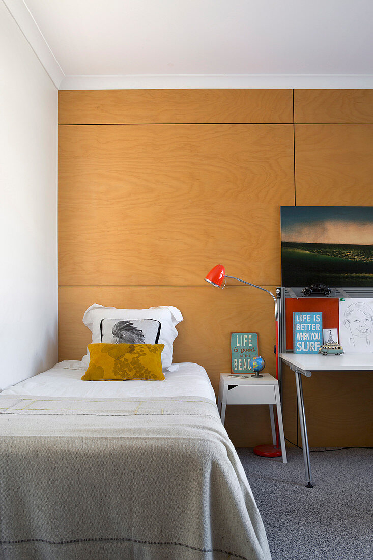 Simple children's room with bed and desk in front of clad wall