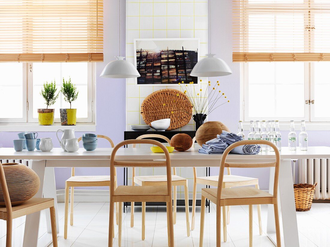 Long white dining table and plain, modern wooden chairs in Nordic dining area