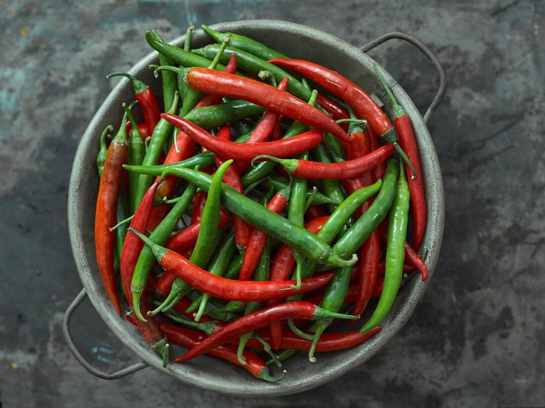 Red and green chilli peppers in a metal bowl