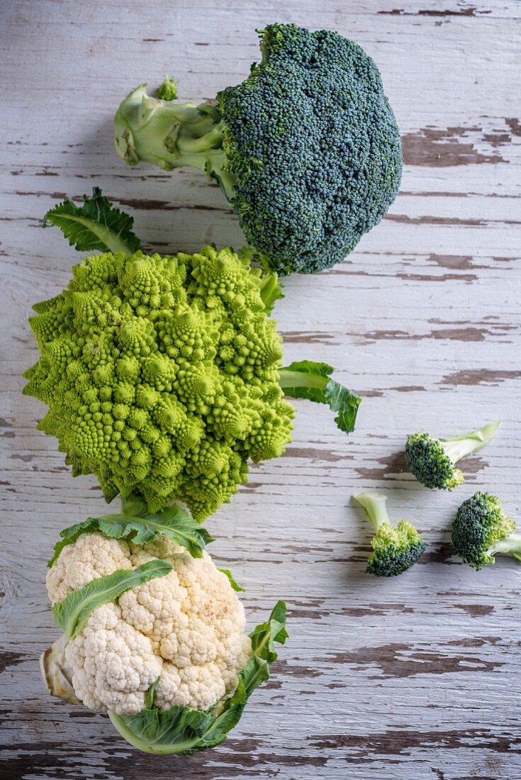 Cauliflower, romanesco and broccoli on a wooden background