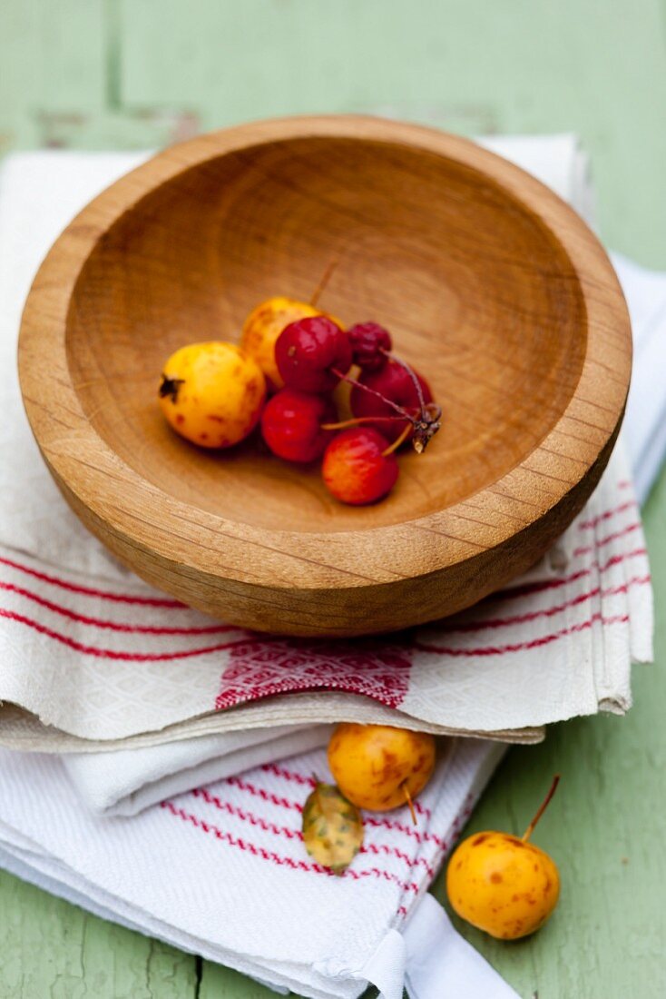 Decorated apples in a wooden bowl on kitchen towel