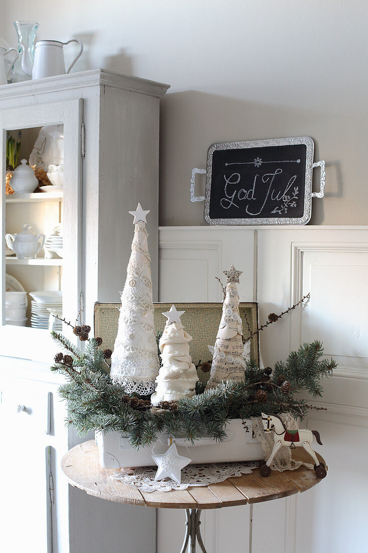 Lacy fabric Christmas trees and fir branches in old suitcase