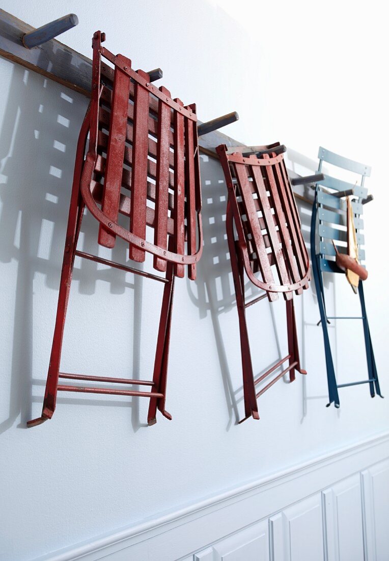 Colourful chairs hanging from wall-mounted hooks