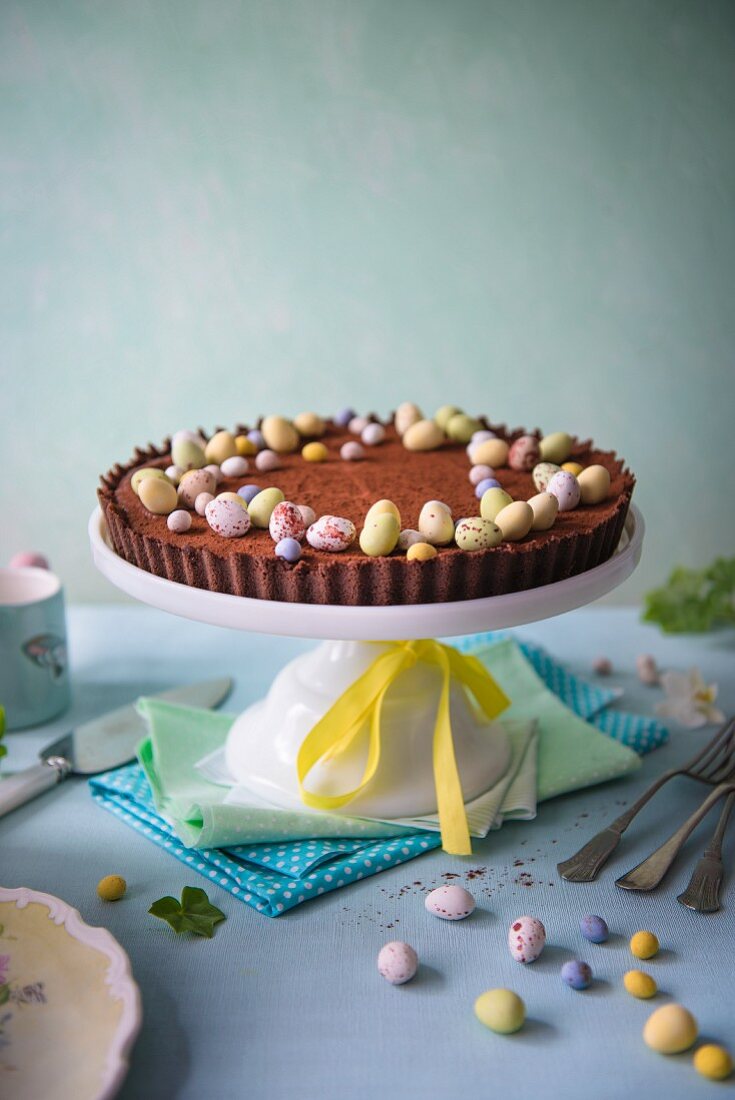 Chocolate tart for easter with easter eggs on a cake stand.