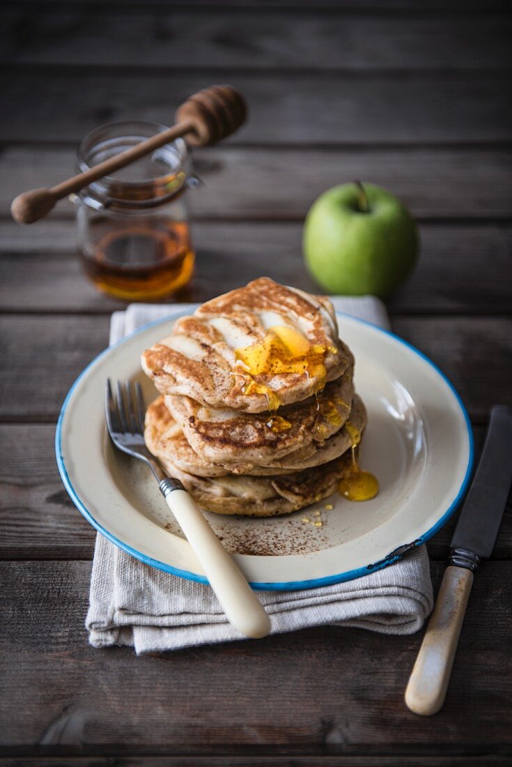 A stack of apple pancakes with honey.
