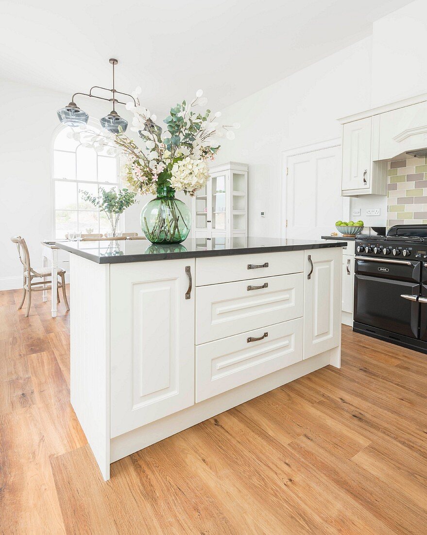 A natural country kitchen with a breakfast bar, granite worktops and a black gas stove