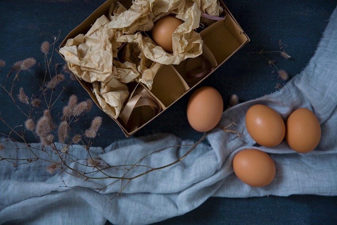 Hühnereier mit Vintage Schachtel , Zweig und pastellblauem Stoff arrangiert