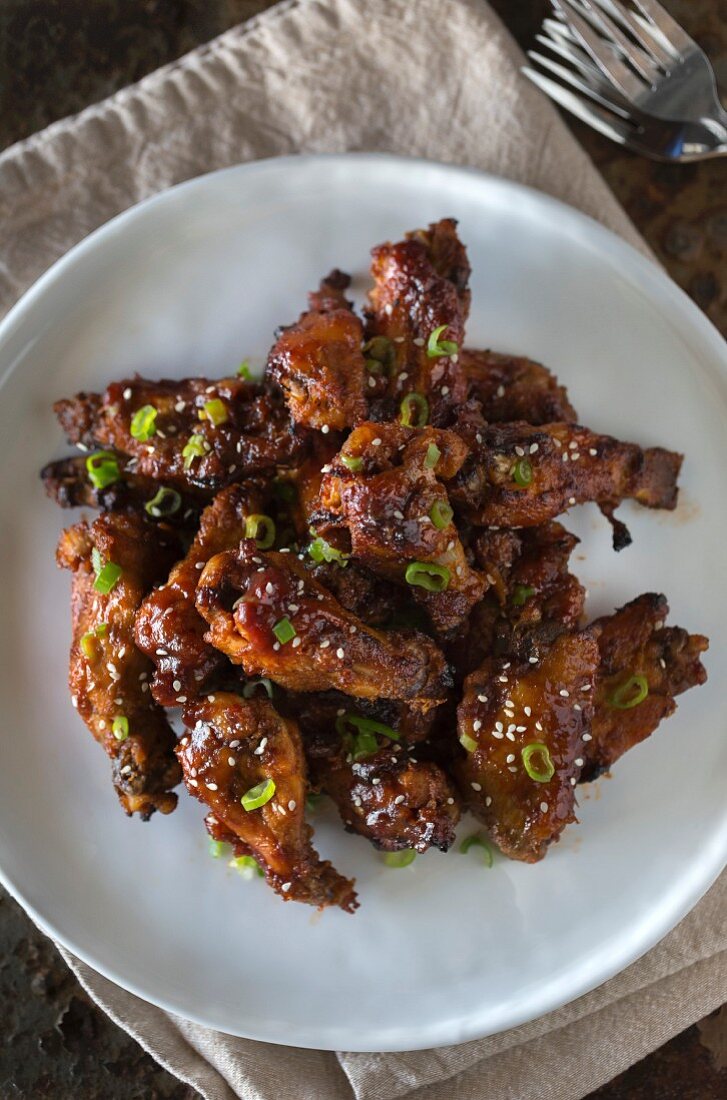 Asian-style sticky chicken wings sprinkled with sesame seeds and spring onions
