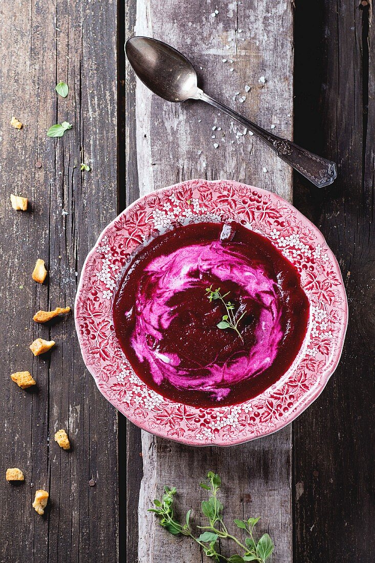 Vintage plate of beetroot cream soup with cream and oregano herbs