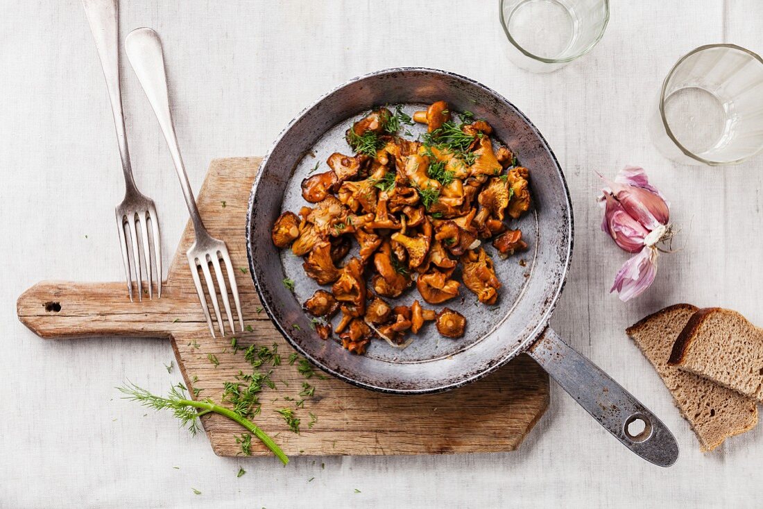 Roasted wild mushrooms in pan on white textured background