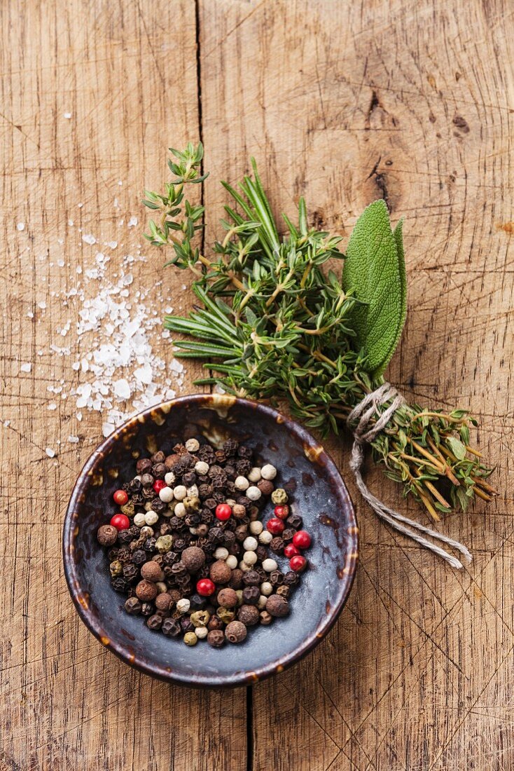 Multicolored peppers peas and spicy herbs on wooden background