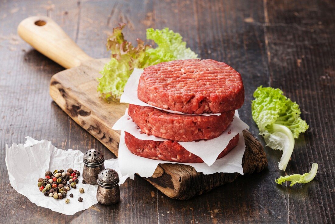 Raw Ground beef meat Burger steak cutlets and seasonings on dark wooden background