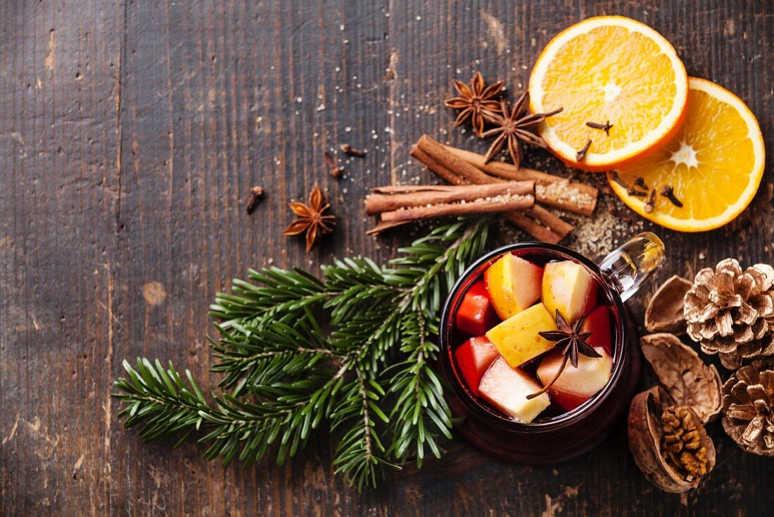 Cup of hot wine with spices on wooden background