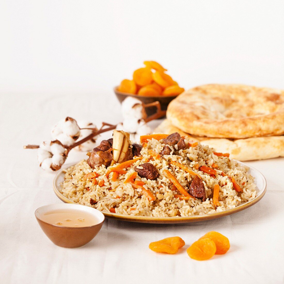 Uzbek national dish pilaf on plate with Uzbek bread and dried apricots