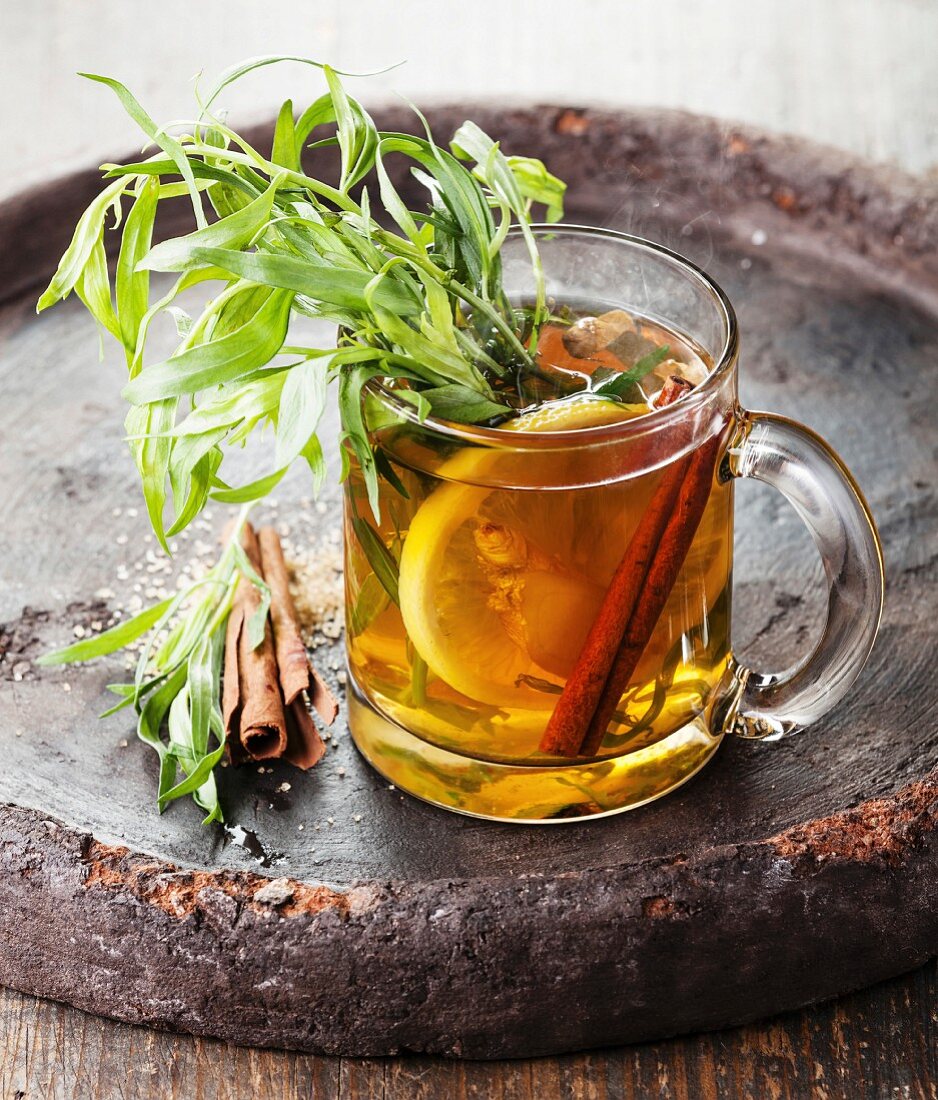 Tarragon hot drink tea with honey, lemon and cinnamon on dark background