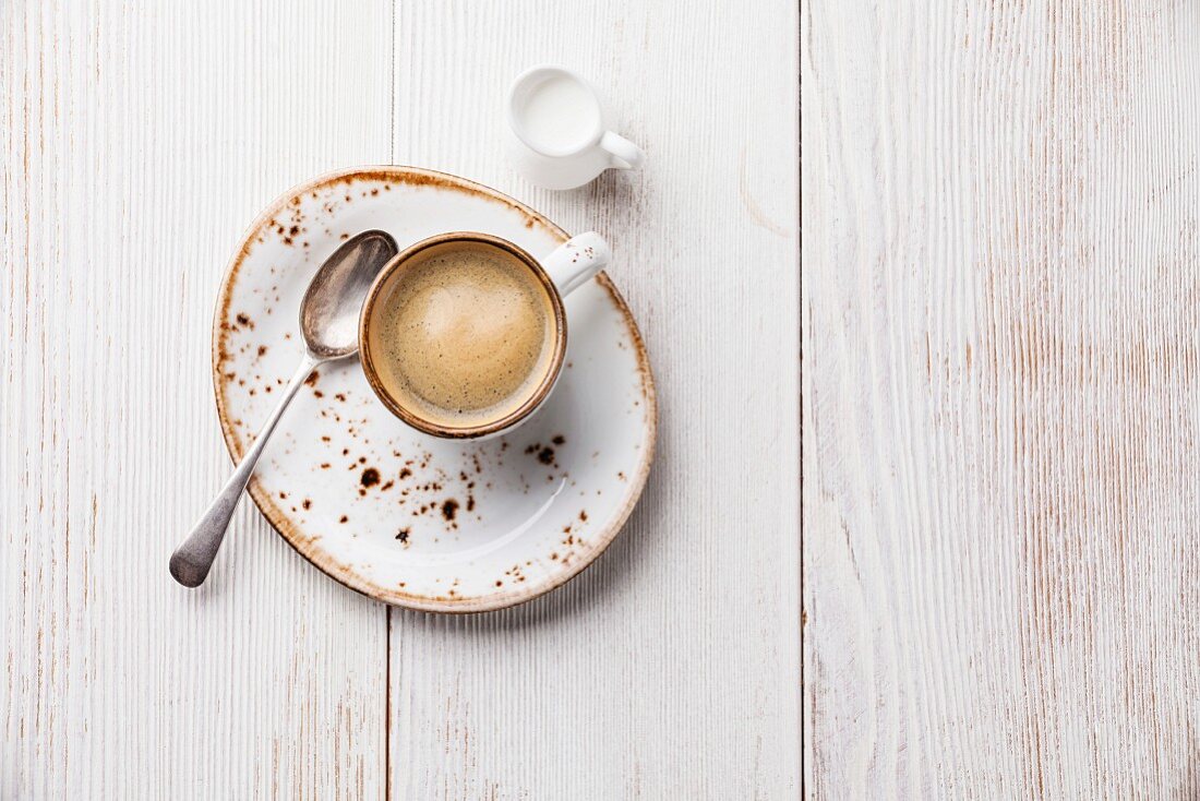 Eine Tasse Kaffee auf weißem Holzuntergrund