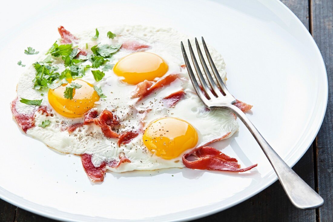 Traditionelles Frühstück mit Spiegeleiern und Speck auf weißem Teller