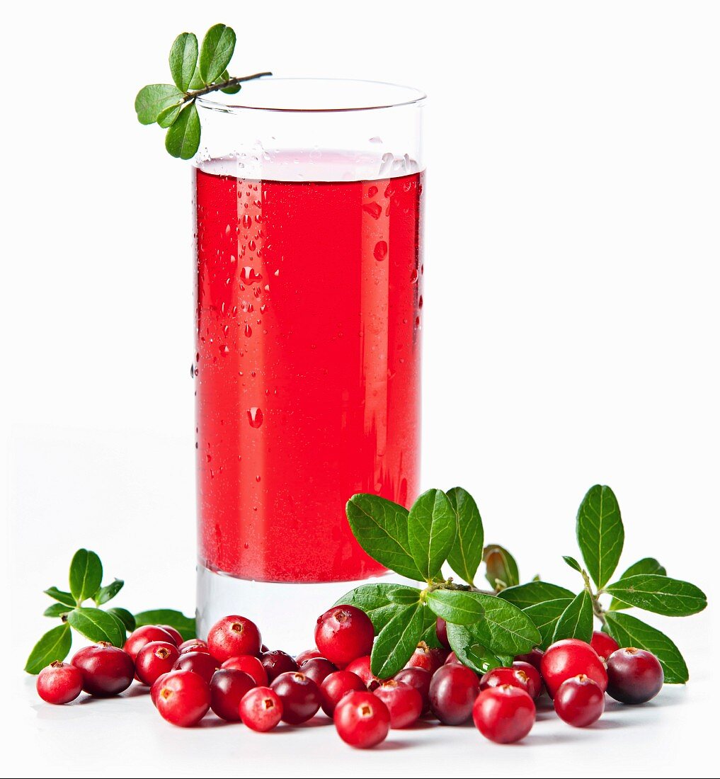 Fruit drink made from cranberries with leaves on white background