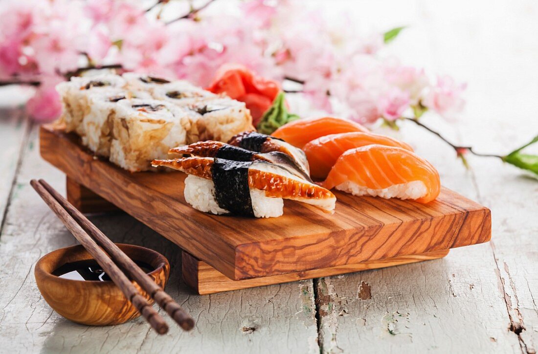 Sushi mit Sashimi und Sushi-Rollen auf Olivenholzplatte