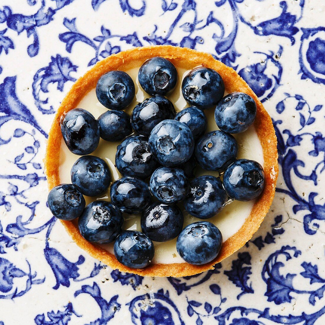 Blueberry tart on blue ornament background