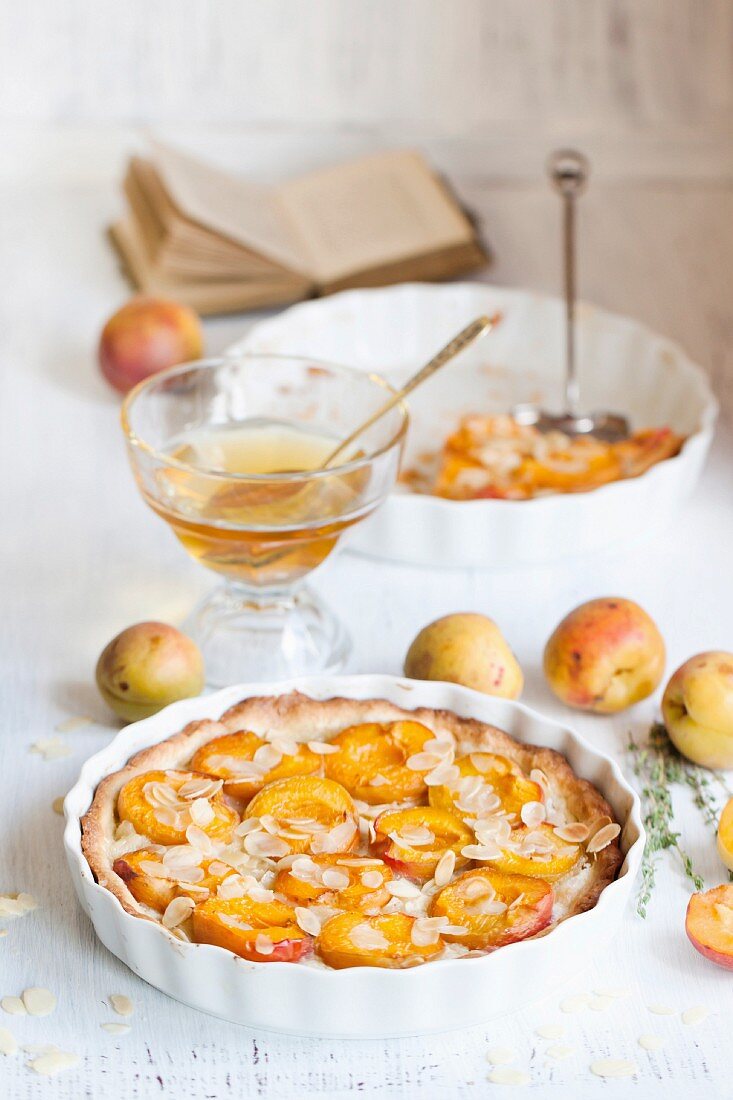 Breakfast with homemade apricot tarte with almonds, fresh apricots and honey on white wooden table