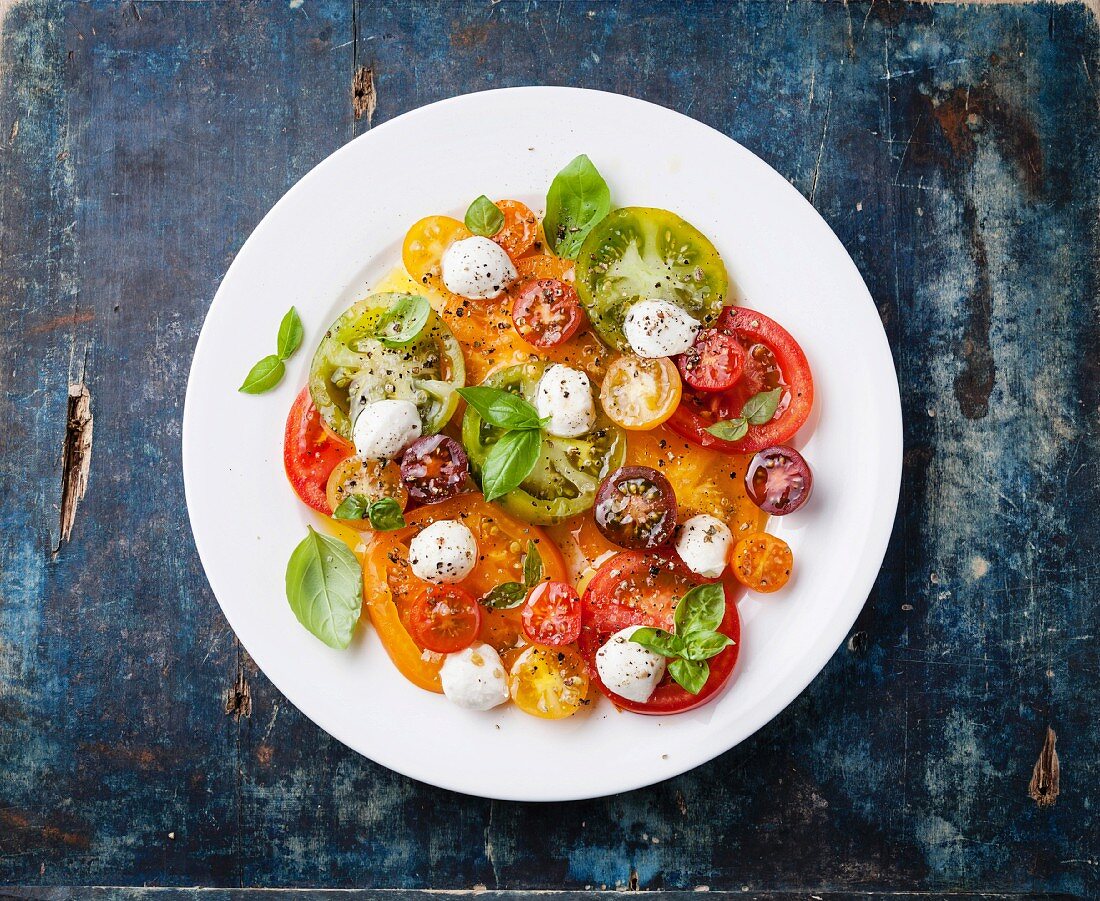 Colorful tomatoes salad with mozarella on blue wooden background