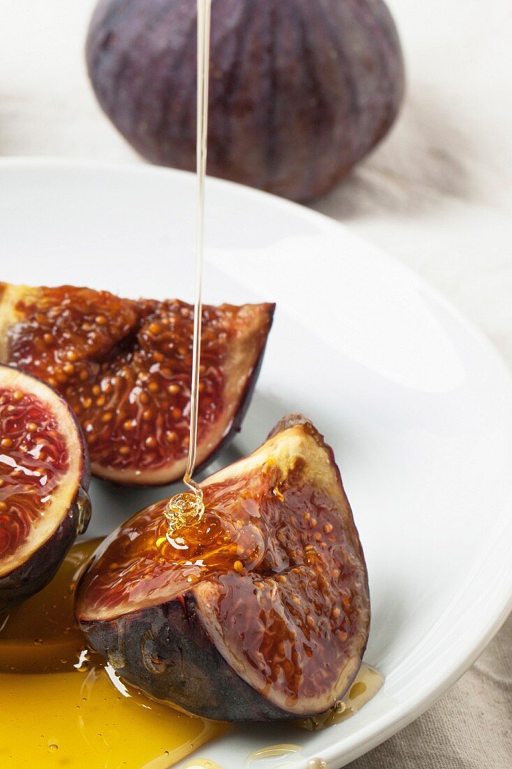 White plate with sliced figs and flowing honey