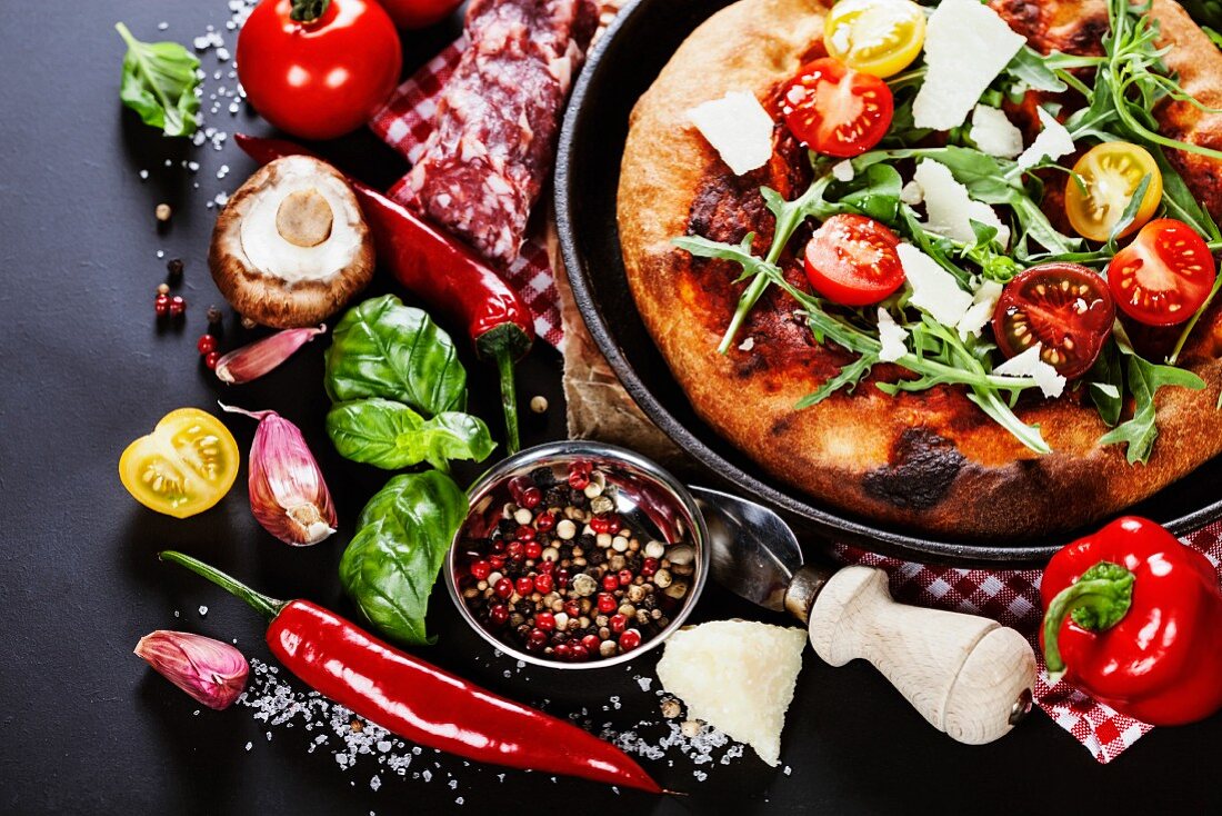 Pizza and fresh italian ingredients on a dark background