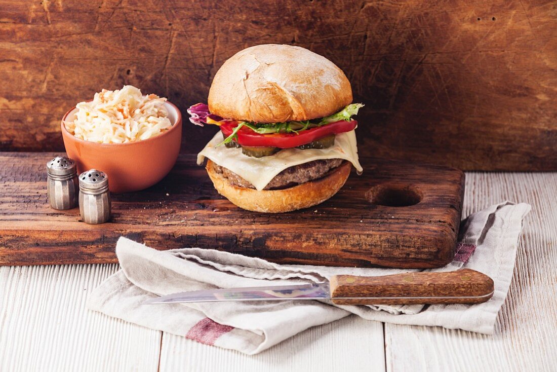 Burger mit Fleisch und Krautsalat auf Holzuntergrund