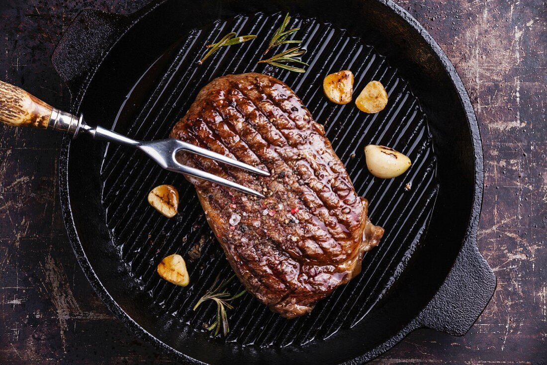 Ribeye Steak in Grillpfanne auf dunklem Hintergrund