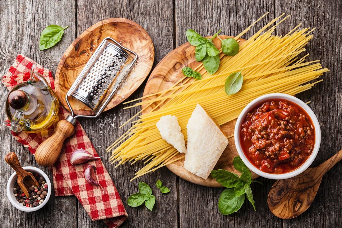 Zutaten für Spaghetti Bolognese auf grauem Holzuntergrund