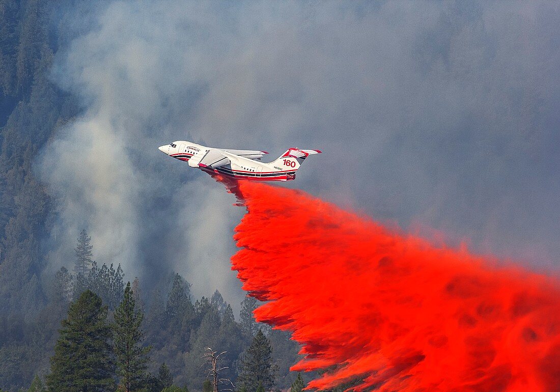 Aircraft releases fire retardant over forest fire