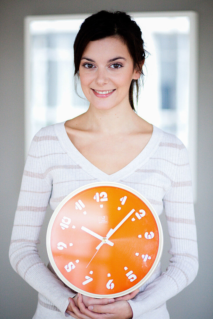 Woman holding orange clock