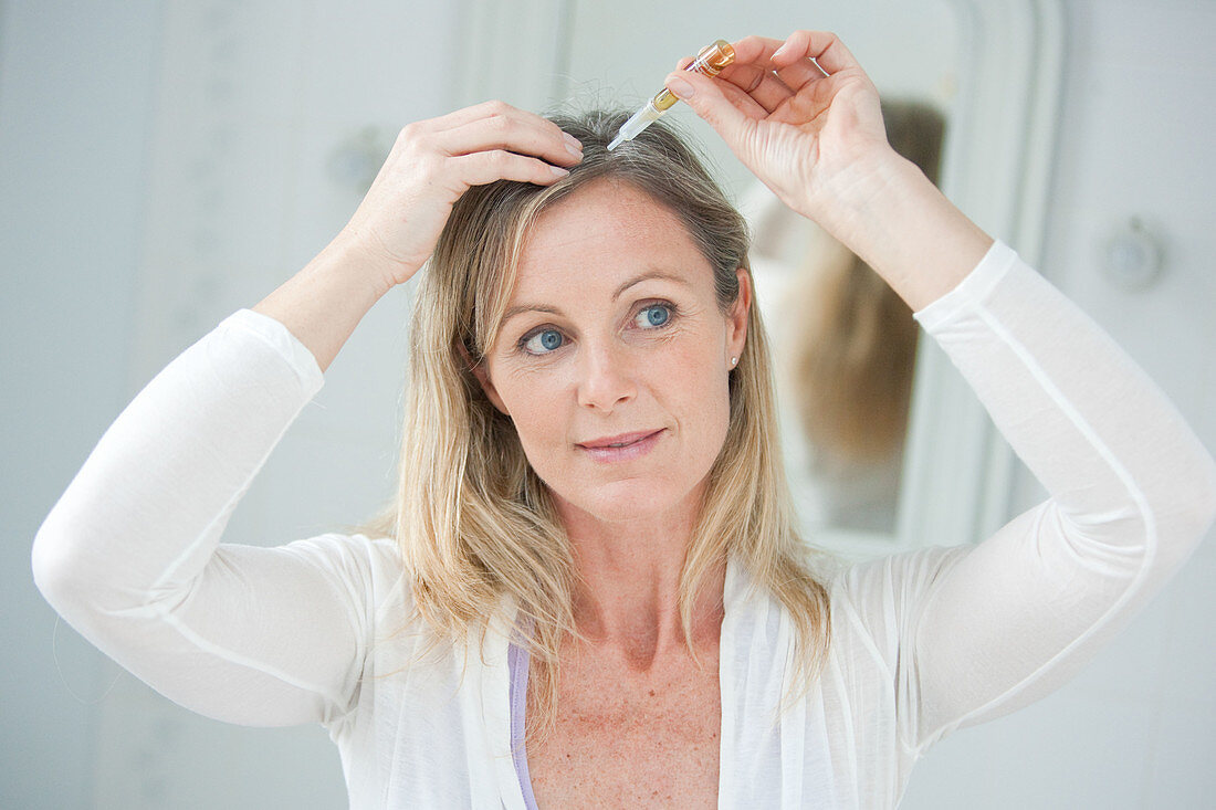 Woman applying hair lotion