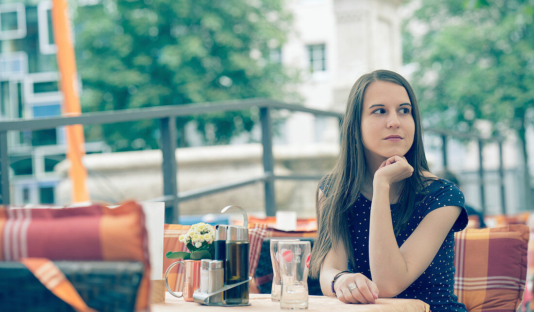 Young woman sitting at table in outdoor cafe