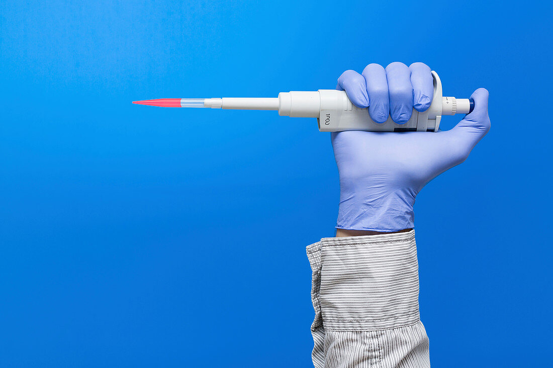 Person wearing latex glove holding pipette