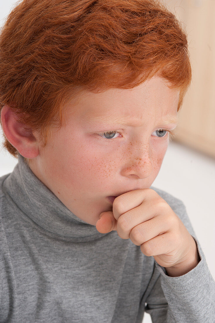 Boy coughing with hand over mouth