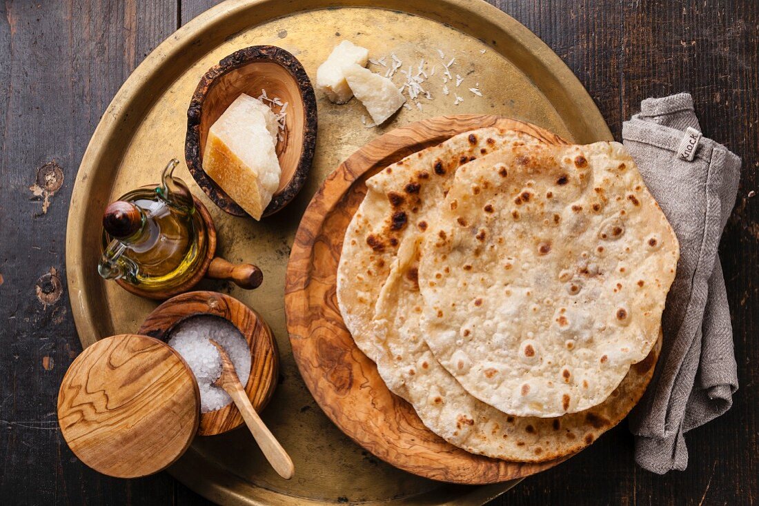 Fried tortilla with cheese on olive wood plate on metal background